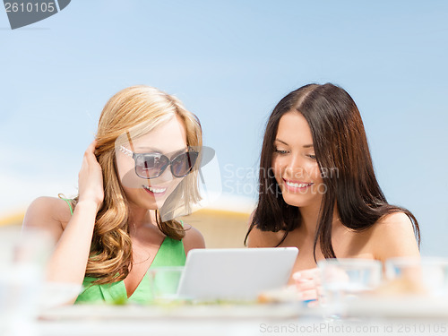 Image of smiling girls looking at tablet pc in cafe