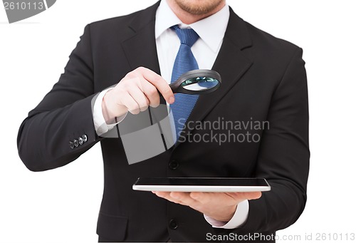 Image of businessman hand holding magnifier over tablet pc