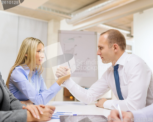 Image of businesswoman and businessman arm wrestling