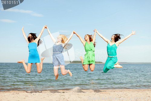 Image of smiling girls jumping on the beach