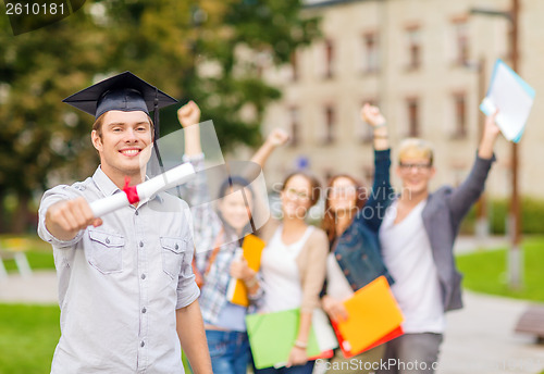 Image of smiling teenage boy in corner-cap with diploma