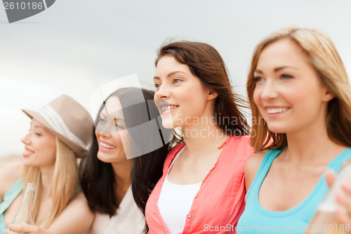 Image of smiling girls with drinks on the beach