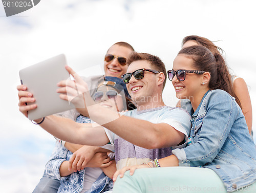 Image of group of smiling teenagers looking at tablet pc