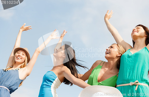 Image of smiling girls with hands up on the beach