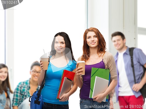 Image of two students with bag, folders, tablet and coffee