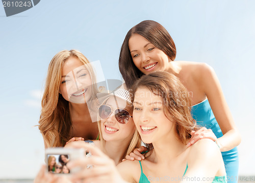 Image of smiling girls taking photo in cafe on the beach