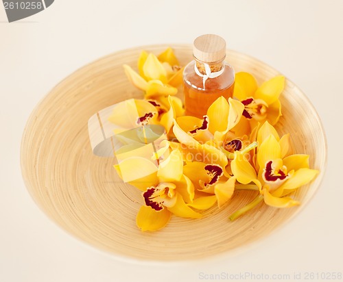 Image of closeup of wooden bowl with orchids and oil