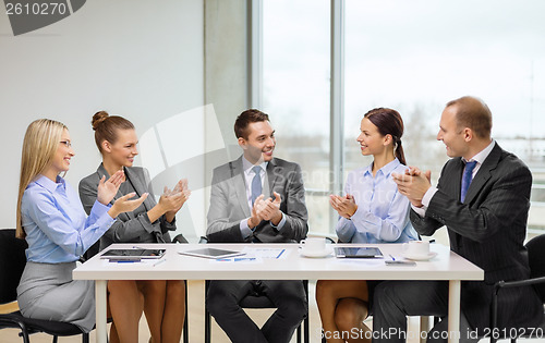 Image of business team with laptop clapping hands