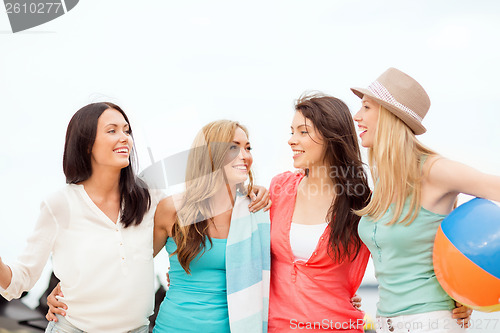 Image of smiling girls with ball and towel on the beach