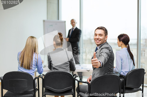 Image of businessman with team showing thumbs up in office