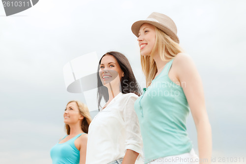 Image of group of smiling girls chilling on the beach