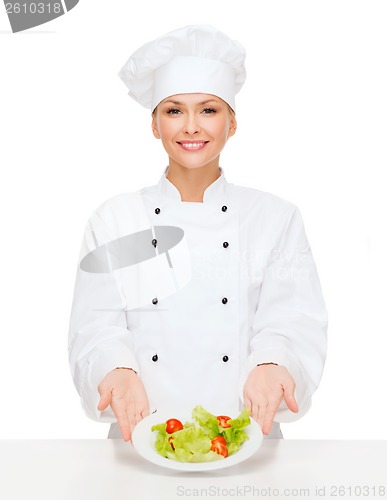 Image of smiling female chef with salad on plate