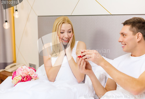 Image of man giving woman little red box and ring in it