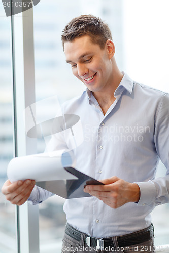 Image of smiling businessman with clipboard in office