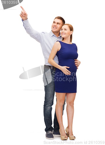 Image of happy young family expecting child pointing finger