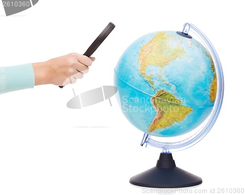 Image of woman hand holding magnifying glass over globe