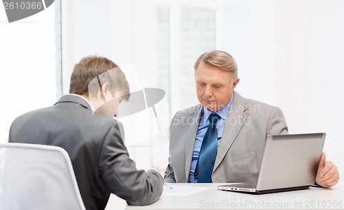 Image of older man and young man signing papers in office