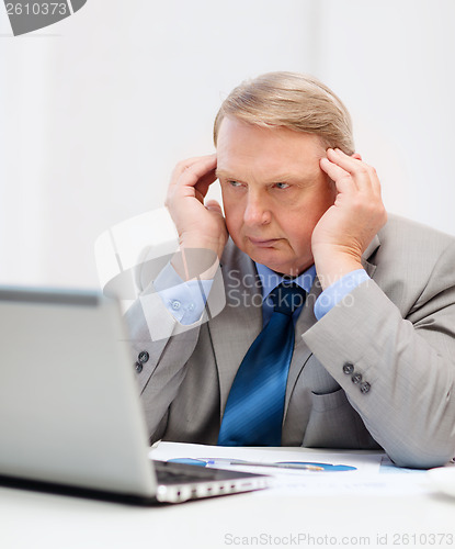 Image of upset older businessman with laptop in office