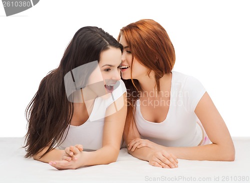 Image of two smiling girls whispering gossip