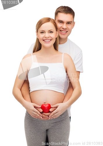 Image of happy young family expecting child with heart