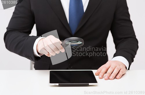 Image of businessman hand holding magnifier over tablet pc