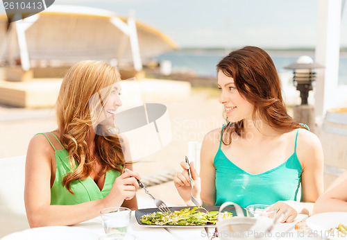 Image of smiling girls in cafe on the beach