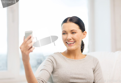 Image of smiling woman with smartphone at home