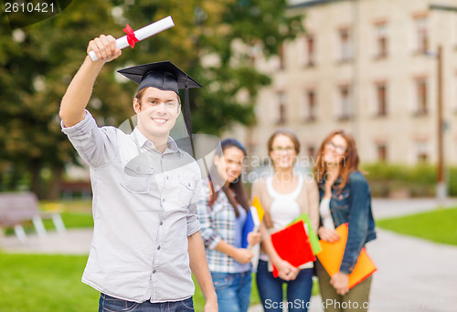 Image of smiling teenage boy in corner-cap with diploma