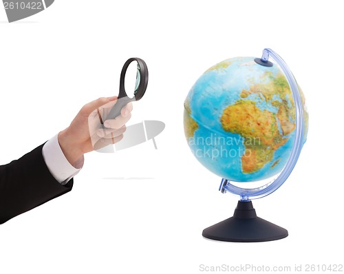 Image of businessman hand holding magnifier over globe