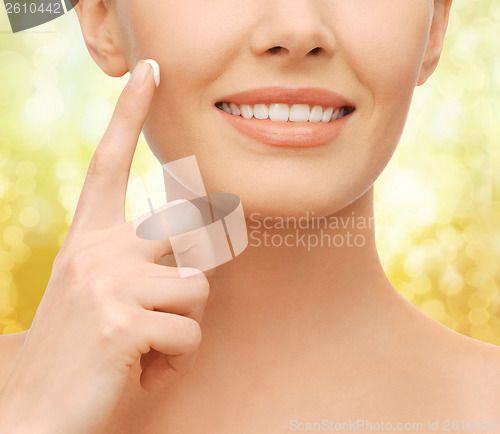 Image of beautiful woman applying moisturizing cream
