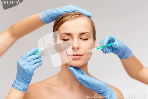 Image of woman face and beautician hands with syringe