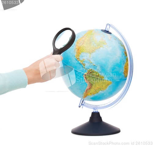 Image of woman hand holding magnifying glass over globe