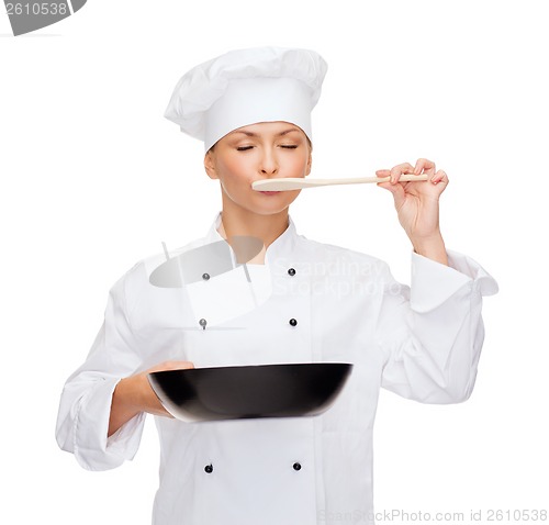 Image of smiling female chef with pan and spoon