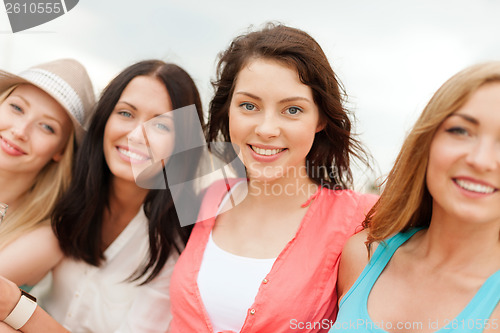 Image of group of smiling girls chilling on the beach