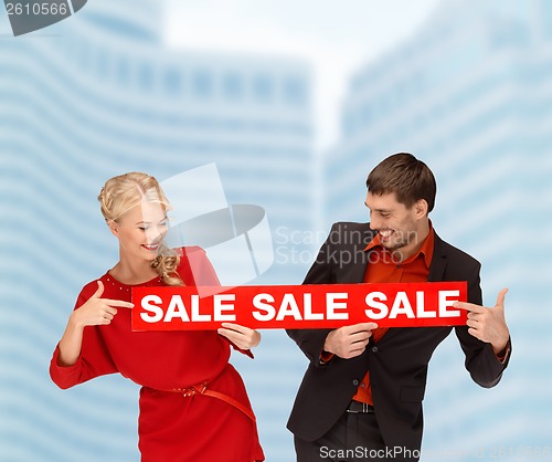 Image of smiling woman and man with red sale sign