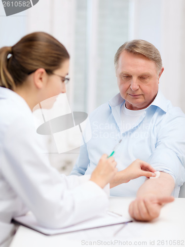 Image of female doctor doing injection to old man