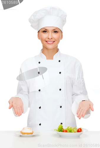 Image of smiling female chef with salad and cake on plates