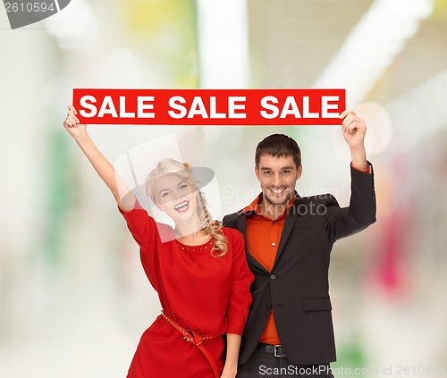 Image of smiling woman and man with red sale sign