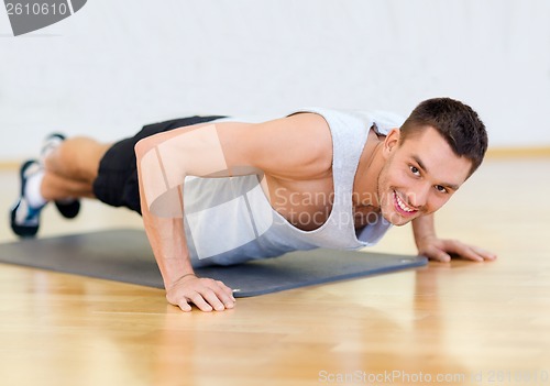 Image of smiling man doing push-ups in the gym