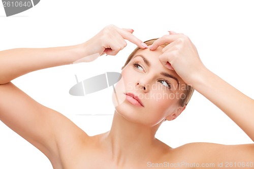 Image of young woman squeezing acne spots