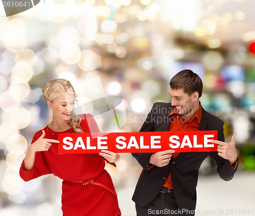 Image of woman and man pointing finger to red sale sign