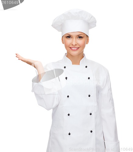 Image of smiling female chef holding something on hand