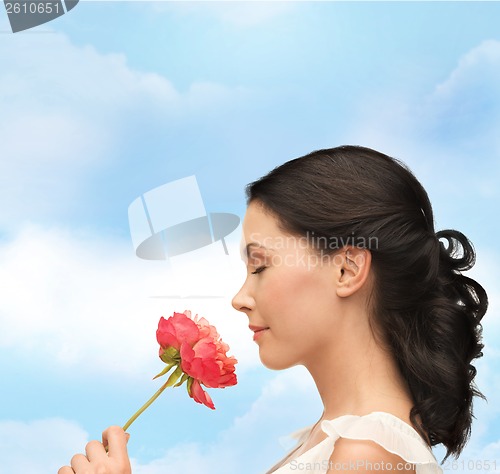 Image of smiling woman smelling flower