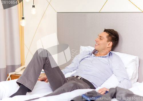 Image of happy businesswoman lying in bed in hotel room