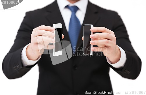 Image of businessman showing smartphones with blank screens