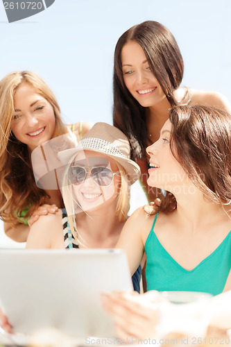 Image of smiling girls looking at tablet pc in cafe