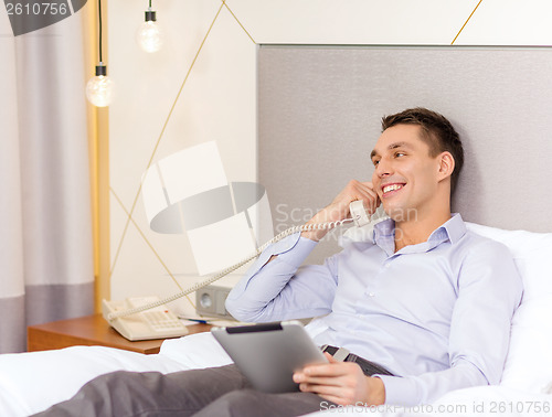 Image of businessman with tablet pc and phone in hotel room