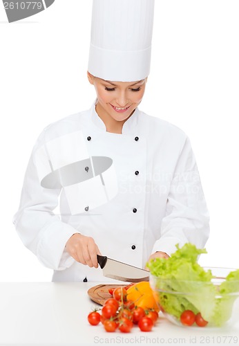 Image of smiling female chef chopping vagetables