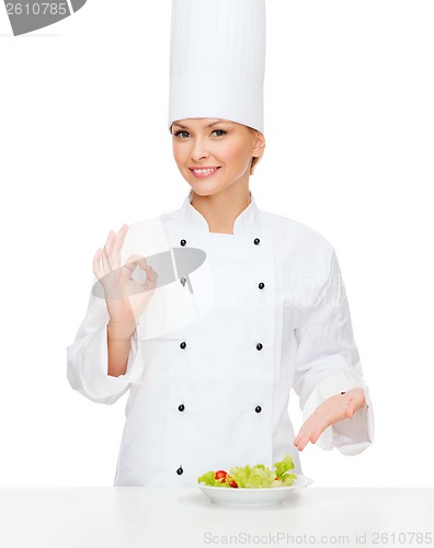 Image of smiling female chef with salad on plate