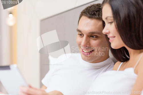 Image of smiling couple in bed with tablet pc computers